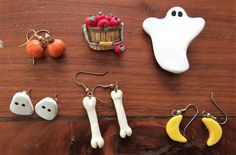 halloween decorations are laid out on a wooden table, including pumpkins and ghost earrings