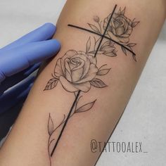 a cross and two roses tattoo on the arm