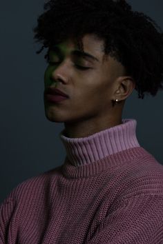 a man with his eyes closed wearing a pink turtle neck sweater and gold hoop earrings