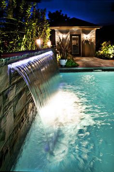 a large pool with a waterfall in it at night