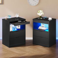 two black tables with blue lights on them in front of a wall clock and wooden floor