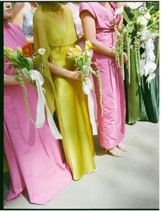 four women in long dresses holding bouquets of flowers and wearing different colored gowns