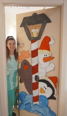 a woman standing in front of a door decorated with snowmen, penguins and a street light