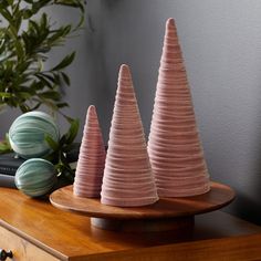 three pink ceramic trees sitting on top of a wooden table