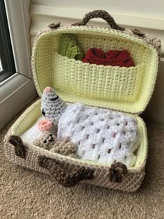 a crocheted suitcase is sitting on the floor next to a window sill