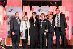 a group of people standing next to each other in front of a pink wall with an american airlines logo on it