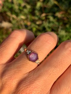 a woman's hand with a ring on it that has a purple stone in the middle