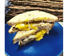 a blue plate topped with a cut in half sandwich next to stack of crackers