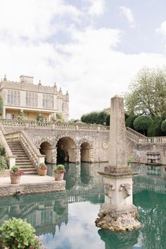 a large building sitting on top of a lush green hillside next to a river filled with water