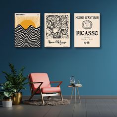 two posters are hanging on the wall above a chair in a room with blue walls