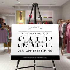 a white sign with the words sale on it in front of clothing racks and clothes