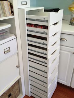 a tall white cabinet with many drawers