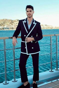 a man in a suit standing on the deck of a boat