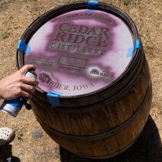 a person is holding a spray bottle near a barrel with the words cedar ridge distiller on it