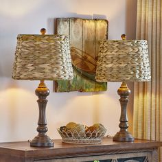 two lamps sitting on top of a wooden table next to a basket filled with fruit