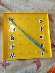 a yellow tray with letters on it and a blue toothpick in the middle