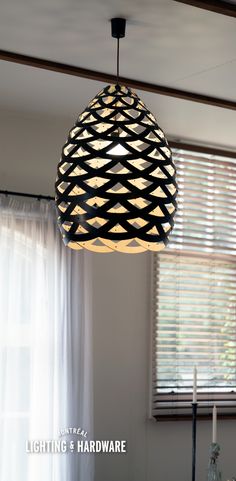 a light fixture hanging from the ceiling in a room with curtains and windows behind it