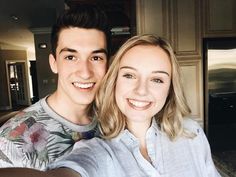 a young man and woman taking a selfie in the kitchen with an open refrigerator behind them