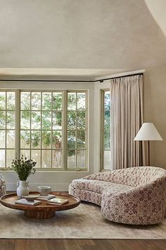 a living room with two couches, chairs and a coffee table in front of large windows