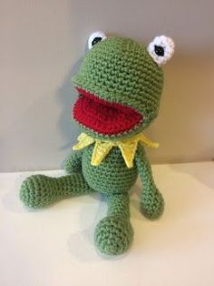 a crocheted frog sitting on top of a white table next to a wall