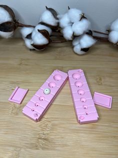 three pink plastic buttons sitting on top of a wooden table next to cotton floss