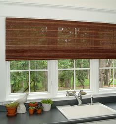 a kitchen sink under a window covered in bamboo blinds