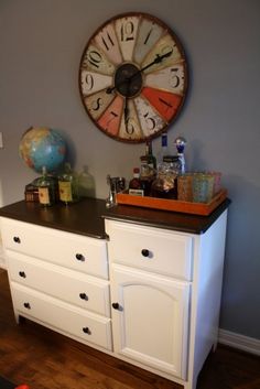 a large clock mounted to the side of a white dresser