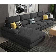 a living room with grey couches and yellow pillows on the floor next to a coffee table