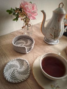 three crocheted coasters and a teapot on a table