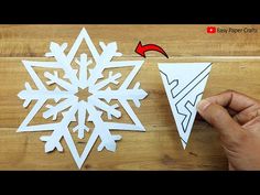 someone is cutting out a snowflake from paper