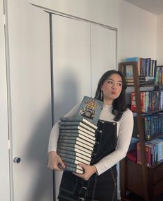 a woman holding an accordion in front of a bookshelf