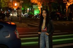 a woman standing in the middle of a street at night with her hand on her hip