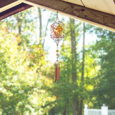 a wind chime hanging from the side of a wooden structure in front of trees