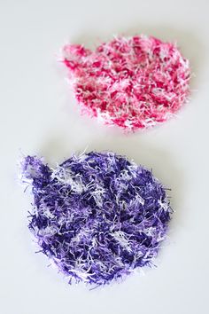 two pieces of purple and pink yarn sitting on top of a white table next to each other