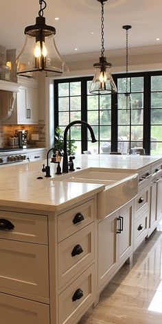 a large kitchen with an island in the middle and two lights hanging from the ceiling