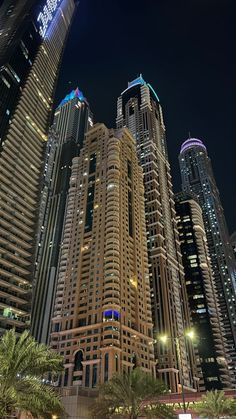 the tall buildings are lit up at night in the middle of the cityscape