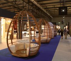 people are walking around an exhibit with circular wooden objects on the blue carpeted floor