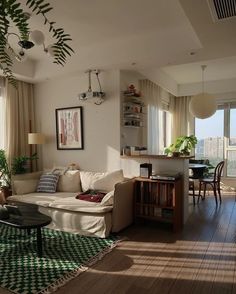 a living room filled with furniture next to a window covered in curtains and potted plants