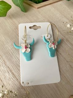 the earrings are made out of clay and have flowers on each earring, along with an elephant's head