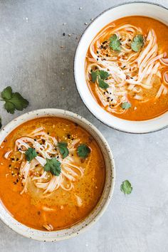 two bowls of soup with noodles and garnishes