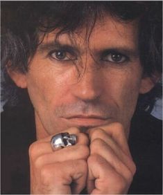 a close up of a person with a ring on his finger and wearing a black shirt