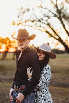 a man and woman standing next to each other wearing cowboy hats