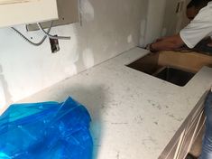 a man is working on a kitchen counter with blue plastic covering the top and bottom