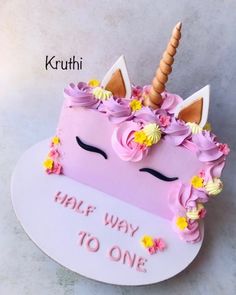 a cake shaped like a unicorn with flowers and a horn on top that says half way to one