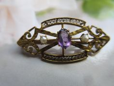 Antique 10K gold amethyst and seed pearl lapel pin. This tiny keepsake dates to the early 1900s and is stamped 10K on the clasp. It will make a lovely lapel pin or tie tack for a man or a woman. The pearl is the traditional birthstone for June and the amethyst represents February. Beautiful for a groom on his wedding day. Our gold antique brooch measures one and three eighths of an inch by five eighths of an inch. age appropriate wear Antique Purple Brooches For Formal Occasions, Antique Purple Formal Brooches, Antique Hallmarked Purple Brooches, Antique Purple Hallmarked Brooches, Purple Victorian Wedding Brooches, Antique Purple Brooches As Gift, Antique Wedding Lapel Pin, Vintage Purple Oval Brooch, Vintage Purple Wedding Brooches