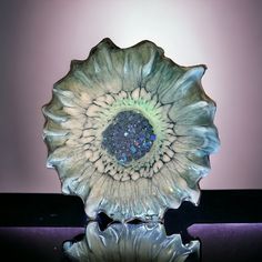 a glass bowl with a flower design on the center and bottom, in front of a purple background