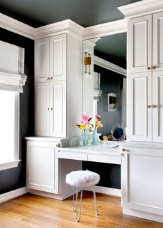 a white vanity in a room with black walls and wooden flooring on the side