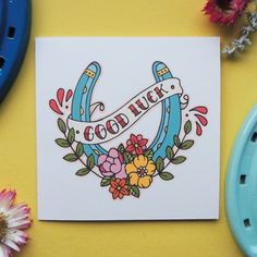 a card with the words good luck on it next to some flowers and blue plates