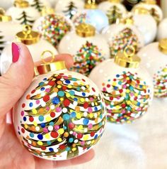 a hand holding a christmas ornament in front of many other baubles