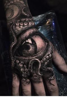 a hand with an octopus tattoo on it and the eye in the middle is open